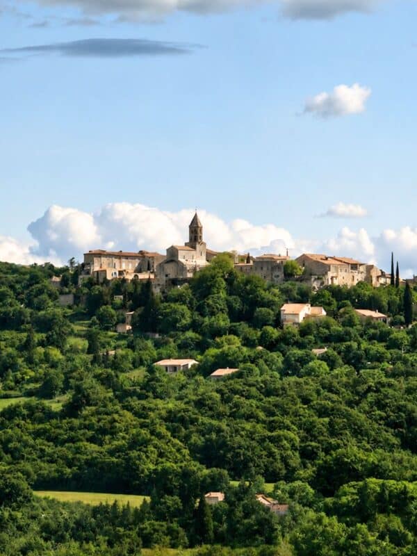 Terracotta-colored hillside village and church viewed from an SNCF train in the South of France